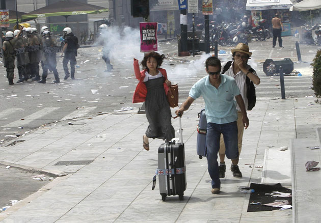 Туристы бегут от слезоточивого газа в центре Афин во время антиправительственных протестов, 15 июня 2011 года